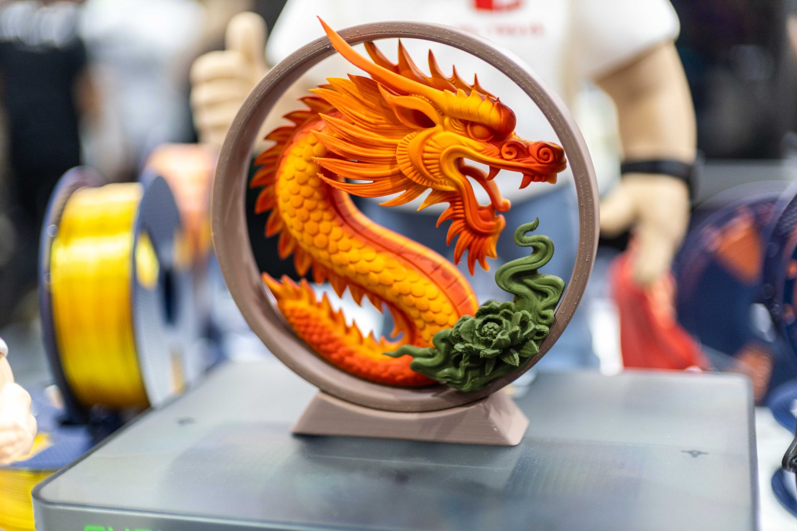Dragão colorido impresso em 3D com alto nível de detalhe em exposição.