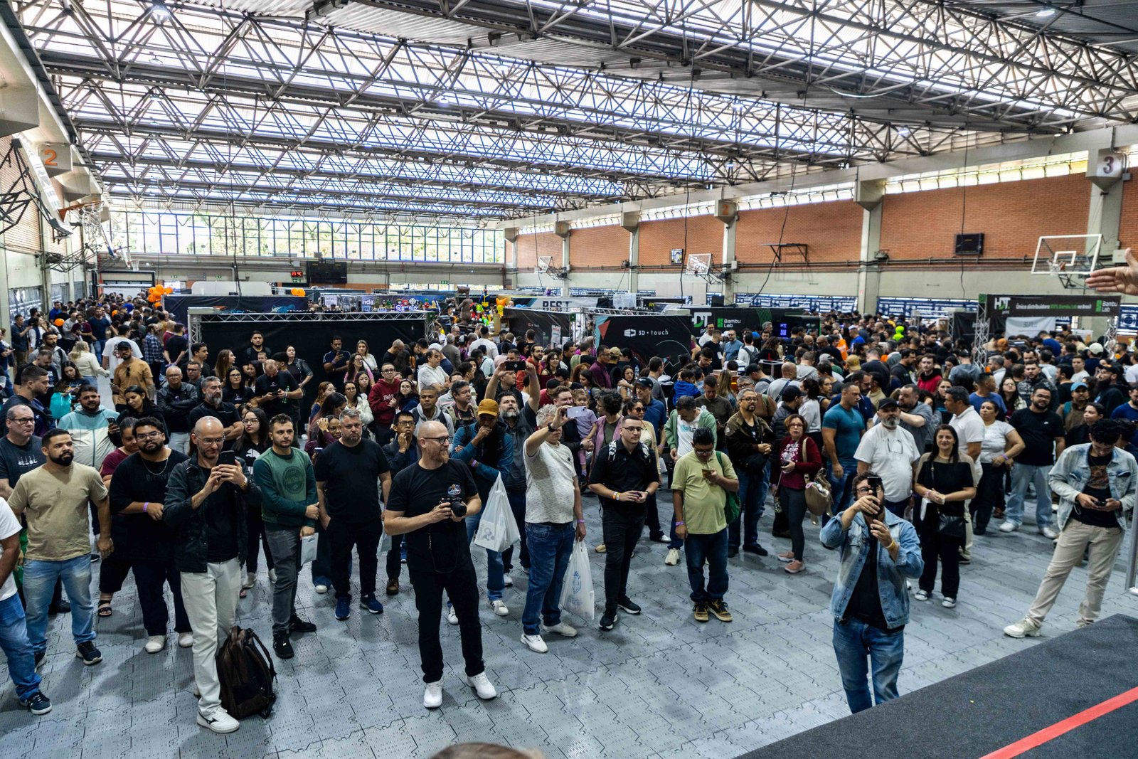 Corredor lotado na Expo3DBR 2026 com visitantes circulando entre estandes de manufatura aditiva.